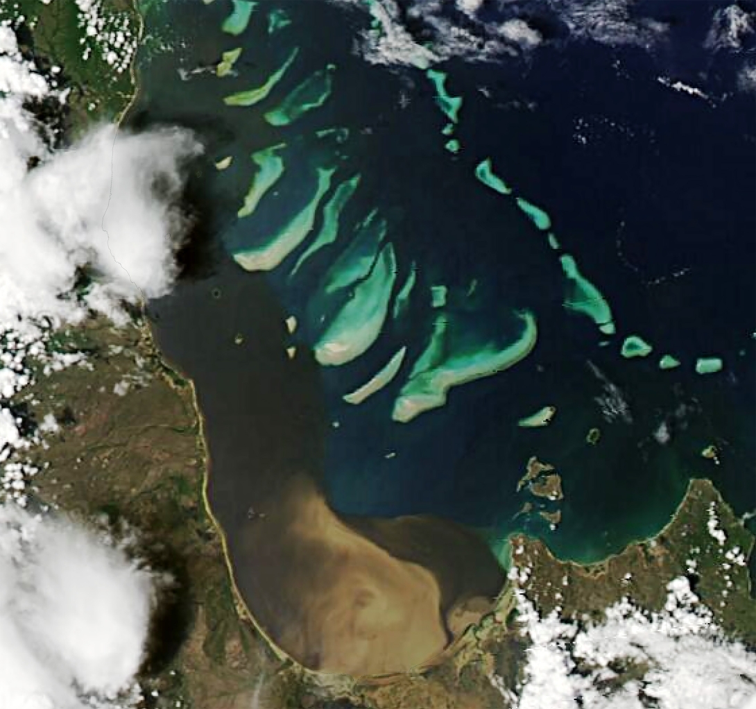 Satellite photo above Princess Charlotte Bay in Far North Queensland showing the brown waters emerging from the Normanby River mouth into the bay and spreading northwards along the coast. The plume surrounds some of the inshore islands and touches some reefs further offshore. The brown waters extend beyond the extent of the image. 