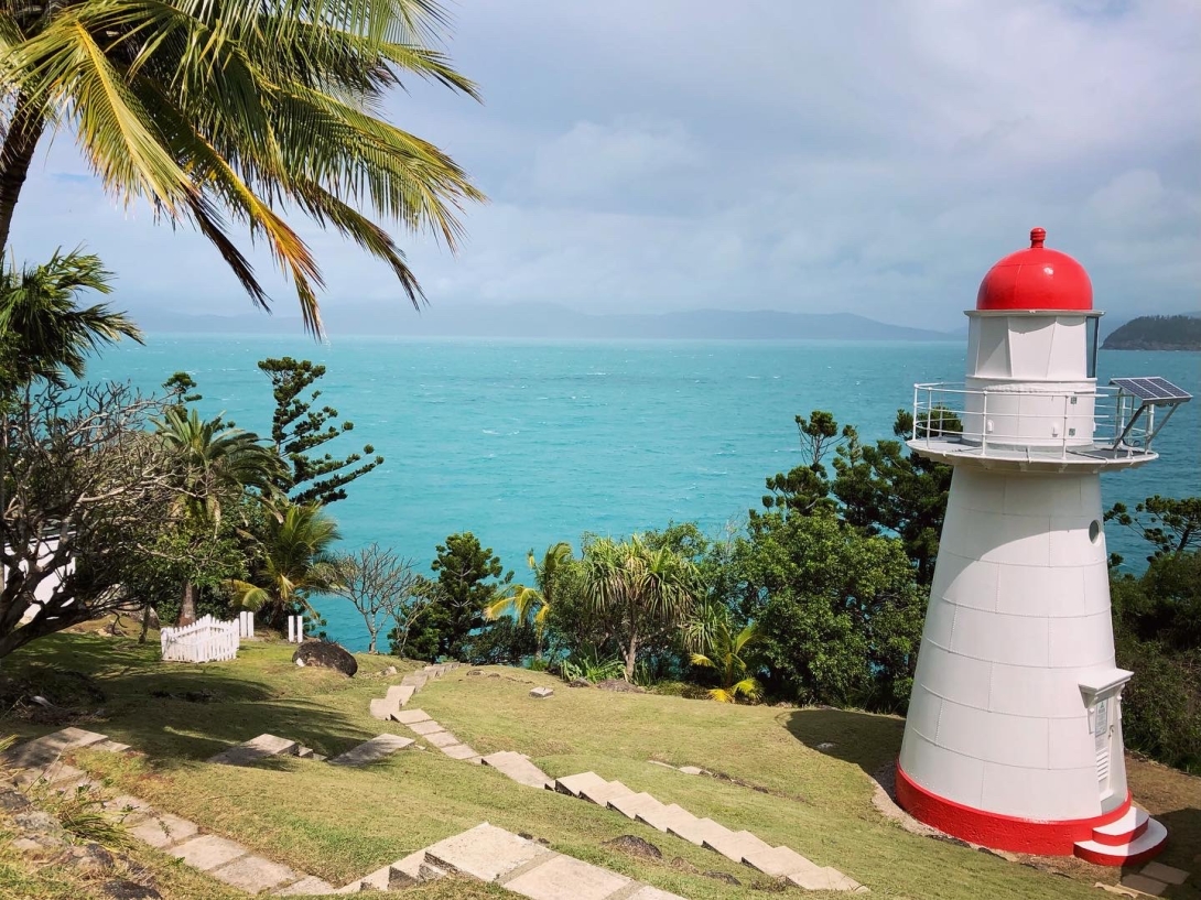 Photograph of a white and red lighthouse with a sea view towards the mainland.