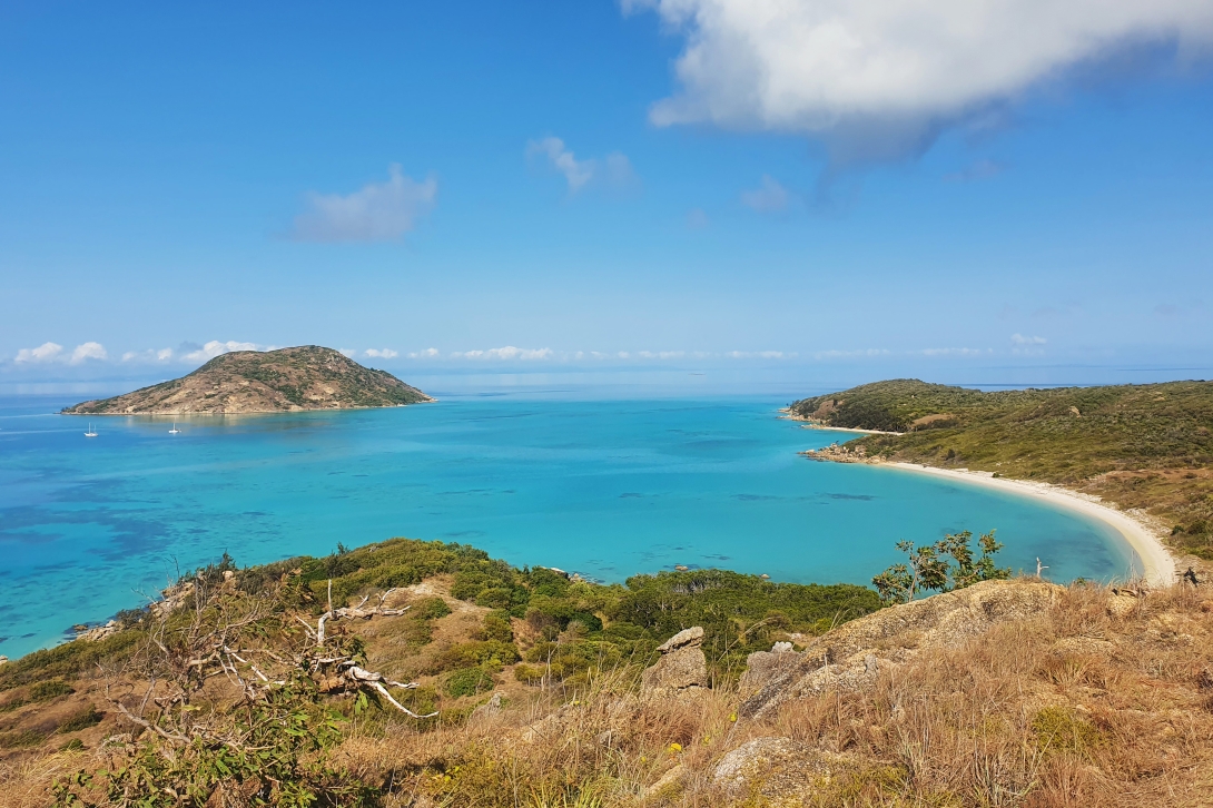 Photograph of a view from Lizard Island (Jiigurru) out to a beach and the blue sea. A second island can be seen in the background.