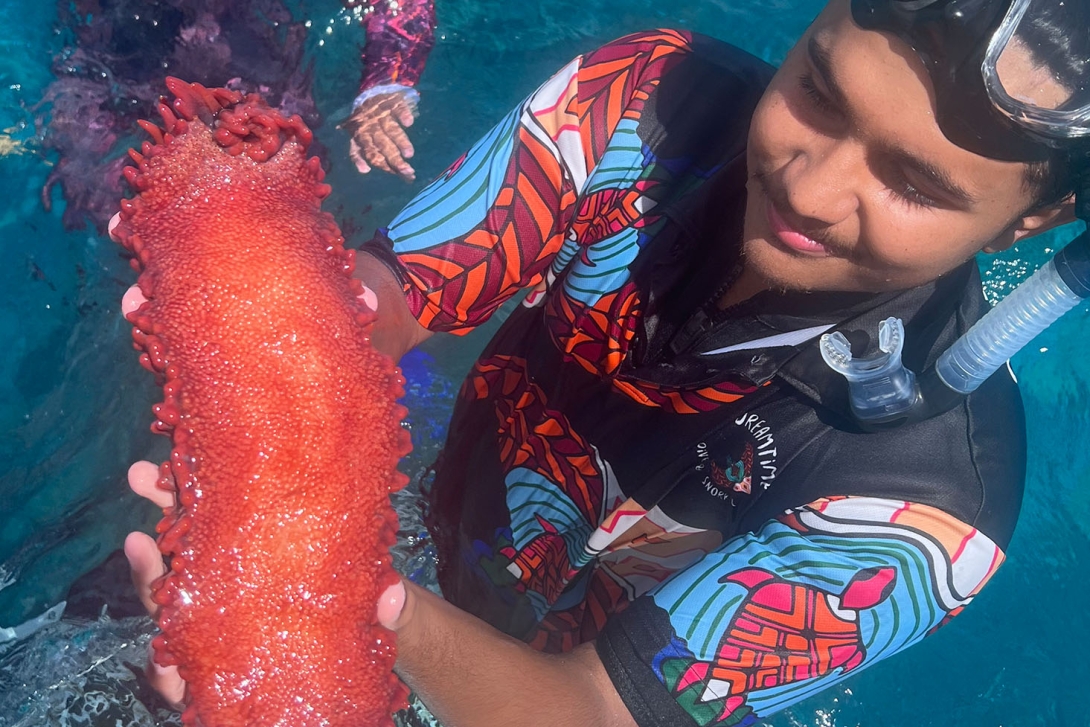 Cultural guide holding a large red sea cucumber.