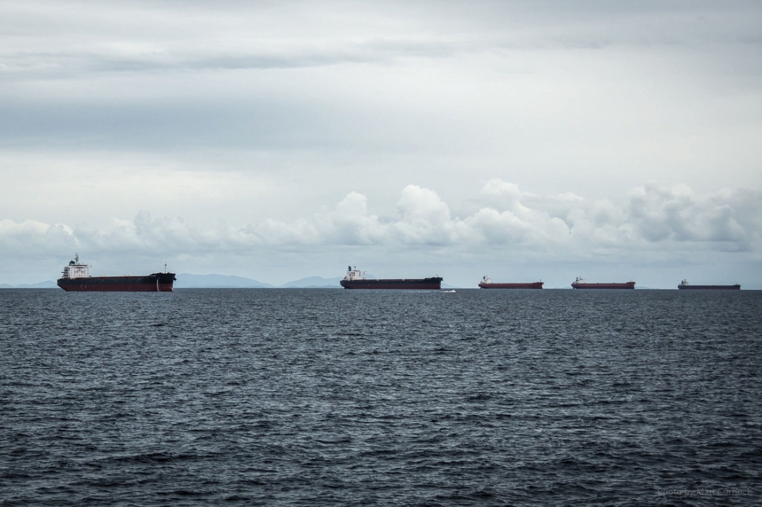 Six large cargo ships anchored on the water.