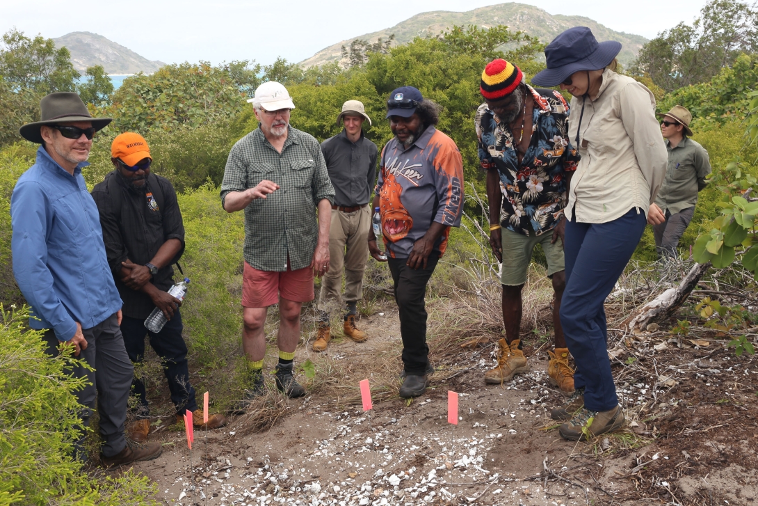 A group of people, consisting of scientists and Traditional Owners, looking at a midden.